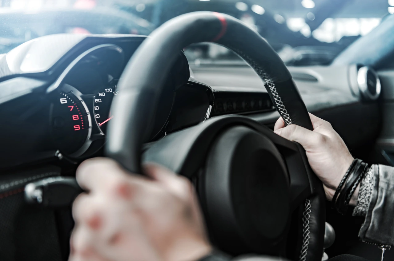 Nahaufnahme von Händen am Lenkrad mit Blick auf Tacho und Armaturen – sicheres Fahrgefühl mit Führerschein mit 17